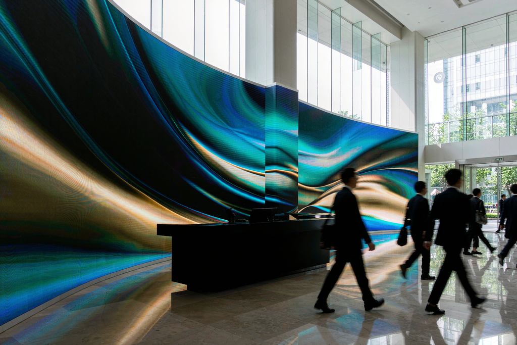 Seamless curved LED screen wall wrapping a column in a modern corporate headquarters lobby