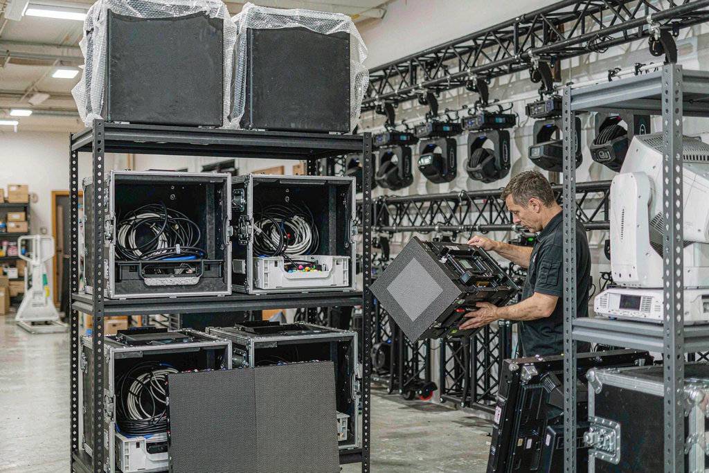 AV rental company warehouse with racks of LED panels in flight cases and a technician inspecting a module