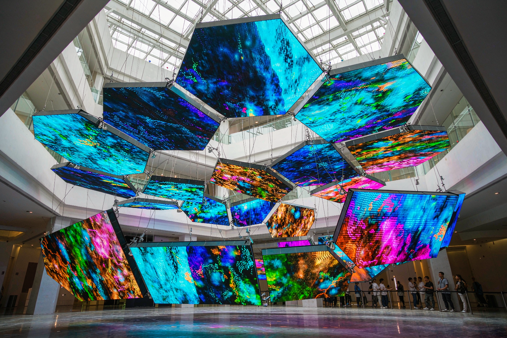 Custom-shaped suspended LED screen panels hanging in a museum atrium