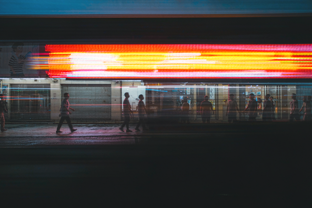 Long-exposure photo capturing the scrolling motion of an LED sign as streaks of light at night