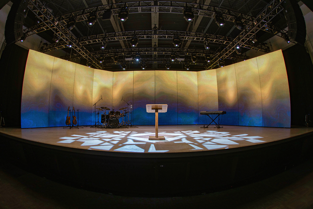 Volunteer media operator switching lyrics, slides and live camera feeds on a church LED wall from the control booth
