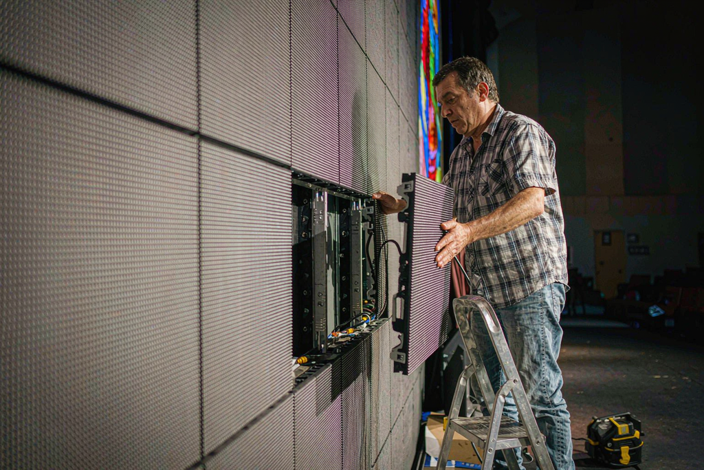 Church volunteer tech team member swapping a single LED panel module on a step ladder in under 30 minutes