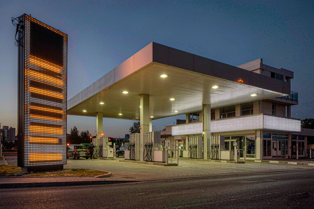 Vertical LED price tower and wide horizontal LED scrolling sign at a gas station forecourt